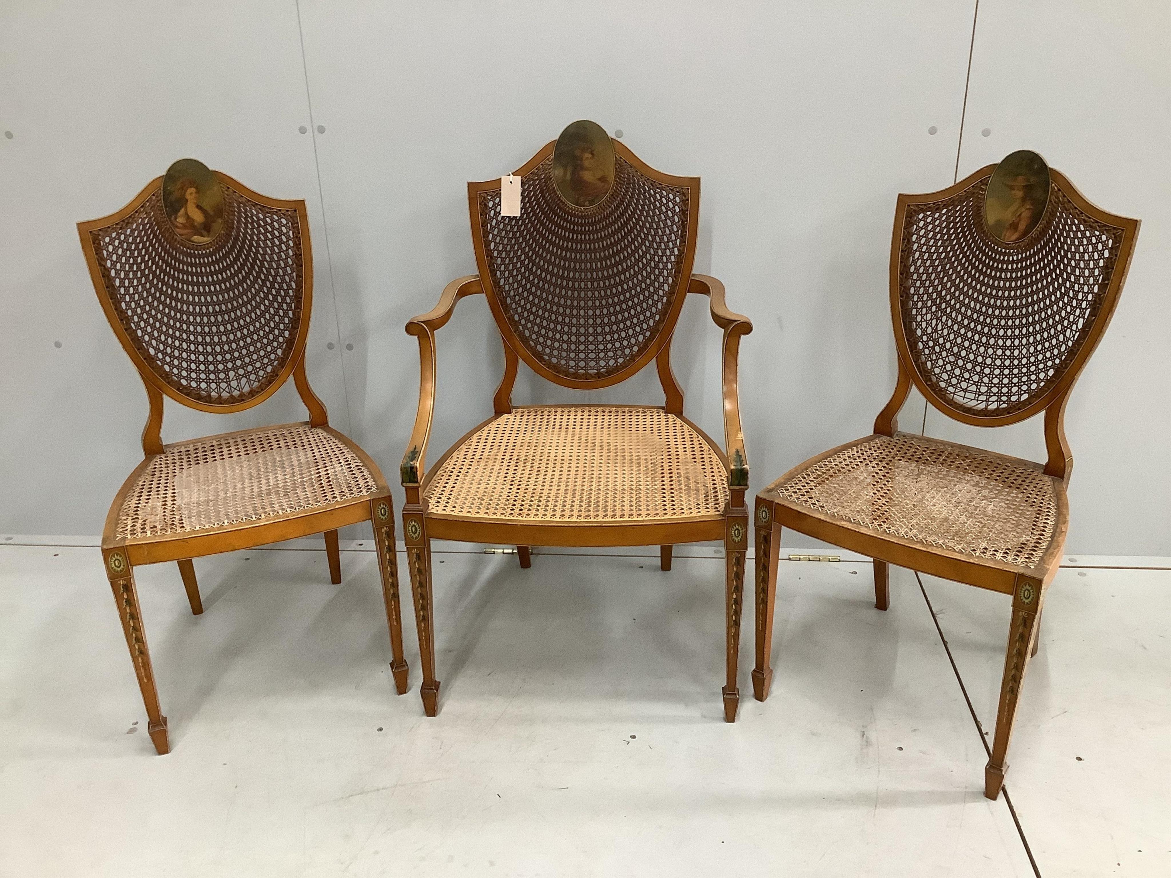 A set of three Edwardian Sheraton Revival painted satinwood caned chairs, one with arms
